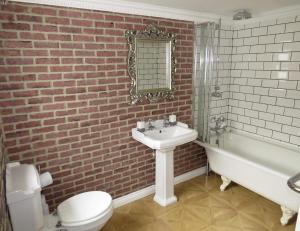 a bathroom with a white sink and a brick wall at Last Cottage in Newbiggin-by-the-Sea