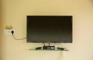 een flatscreen-tv aan een muur bij Laxmi's Apartment - Coconut Grove Residence in Orlim