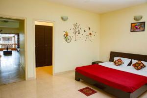 een slaapkamer met een bed met een rode deken bij Laxmi's Apartment - Coconut Grove Residence in Orlim