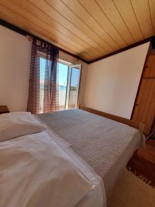 a bedroom with a large bed with a window at Rab Apartment LUCE in Barbat na Rabu