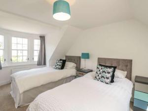 two beds in a room with white walls and windows at Monboddo Townhouse in Auchenblae