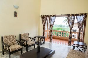 een woonkamer met stoelen en een groot raam bij Laxmi's Apartment - Coconut Grove Residence in Orlim