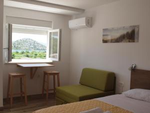 sypialnia z zielonym krzesłem i oknem w obiekcie Apartman&Studio S w mieście Ploče