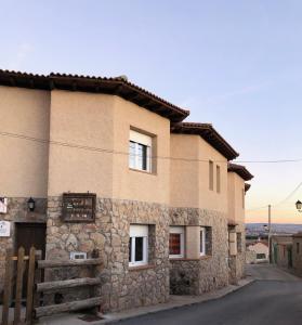 ein Steinhaus mit einem Zaun davor in der Unterkunft Casas Encinares in Narrillos de San Leonardo