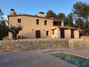 una casa con una pared de piedra y una piscina en CAL PUIG, ENOTURISMO RURAL entre Viñas y Bosques, en Juncosa