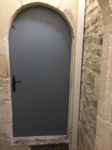 une porte de garage grise dans un mur en pierre dans l'établissement Studio climatisé, La Cloison, à Arles