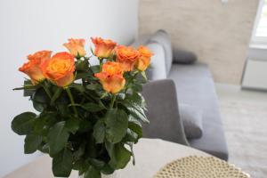 un ramo de rosas naranjas en un jarrón sobre una mesa en Apartamenty 19 en Władysławowo
