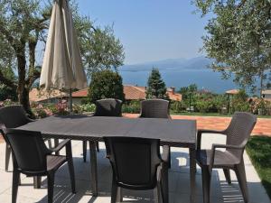 a black table and chairs with an umbrella at Appartamento Lago di Garda Albisano in Torri del Benaco