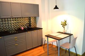 a kitchen with gray cabinets and a table and a table and chairs at Apartament przy Parku in Polanica-Zdrój