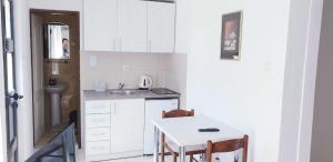 eine kleine weiße Küche mit einem Tisch und einem Waschbecken in der Unterkunft Apartmani Kovačević in Kotor