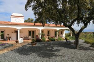 a house with a tree in front of it at Monte Novo da Sobreira, rust en ruimte in zuid Alentejo in Ourique +6 photos