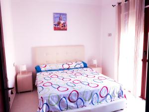um quarto branco com uma cama com um edredão colorido em Oued Laou Apartment em Oued Laou