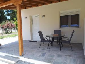 a patio with a table and chairs and a window at Villa Kallimanis in Platanidia