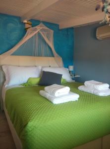 スカラ・ケファロニアにあるPoseidon Apartmentsのベッドルーム1室(緑色のベッド1台、タオル付)