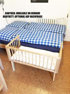 a wooden crib with a blue and white checkered sheet at Appartement über dem Kino Toni in Berlin