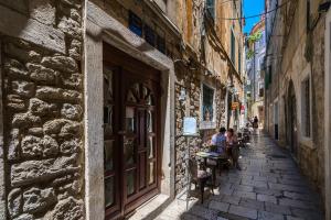 two people sitting at tables on an alley way at Rooftop city view apartment in the palace walls in Split