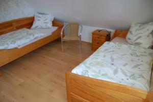 a bedroom with two beds and a chair in it at Ferienwohnung Wiekenblick in Wiesmoor