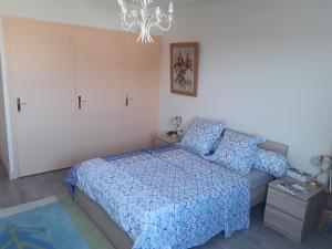 a bedroom with a blue bed and a chandelier at L'Escale in Rochefort