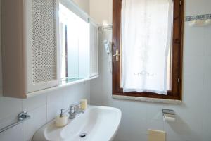 a white bathroom with a sink and a window at Rosa Holiday Home in Villasimius +32 photos