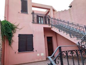 a pink building with a staircase and a balcony at Sa Corti Antiga Apartment in SantʼAntìoco