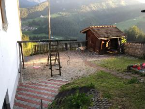 un patio trasero con un columpio y una casa de madera en Fless, en San Martino in Badia