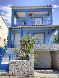 ein blaues Haus mit einem Balkon und Blumen in der Unterkunft Maisonette Ilios in Plisioí