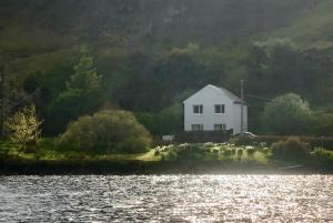 a white house on an island in the water at Storr Apartments in Portree