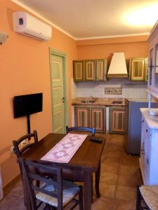 a kitchen with a wooden table with chairs and a television at Sa Corti Antiga Apartment in SantʼAntìoco