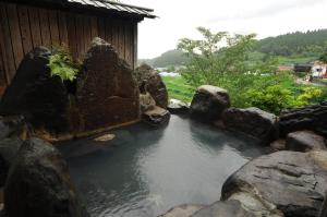 a pond with rocks in front of a building at Ryokan Yunosako in Minamioguni