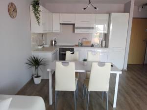 オポーレにあるApartament Marzenie 9 - Opoleの白いキャビネットとテーブルと椅子のあるキッチン