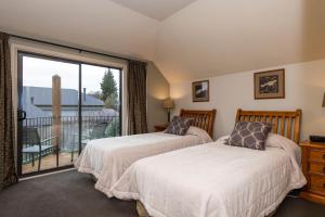 two beds in a room with a balcony at Wanaka Luxury Apartments in Wanaka