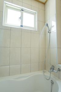 eine Dusche in einem Badezimmer mit Badewanne und Fenster in der Unterkunft Bai Shengcun Homestay in Guoxing + 10 Fotos