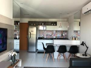 a kitchen with black chairs and a refrigerator at Apto Luxo Iloa Barra de São Miguel in Barra de São Miguel