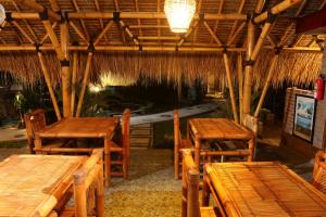 un restaurante con mesas y sillas de madera y techo de paja en Senggigi Cottages Lombok en Senggigi 