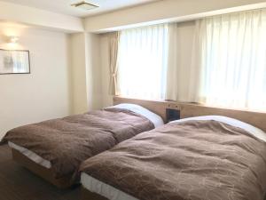 2 Betten in einem Hotelzimmer mit Fenster in der Unterkunft Ichinomiya Green Hotel in Ichinomiya