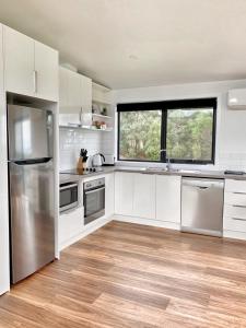 a kitchen with white cabinets and a large window at By Moonlight in Wattle Hill
