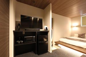 Un dormitorio con una cama y un televisor de pantalla plana. en GRAND BASE Hakata City, en Fukuoka