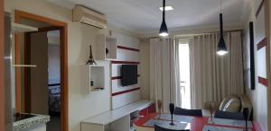 Zimmer mit einem Tisch, Stühlen und einem TV in der Unterkunft Apartamento Giardino Rio Quente in Rio Quente