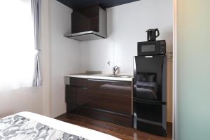 a small kitchen with a sink and a microwave at GRAND BASE Hakata City in Fukuoka