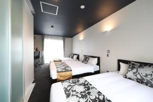 a hotel room with two beds and a window at GRAND BASE Hakata City in Fukuoka
