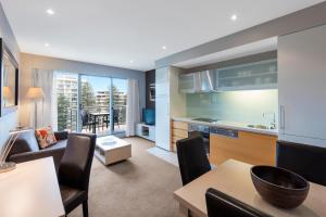 a kitchen with a dining room table and chairs at Apartments @ 16 Holdfast in Glenelg