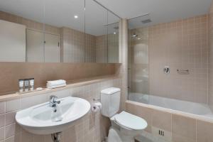 a bathroom with a sink, toilet and bathtub at Apartments @ 16 Holdfast in Glenelg