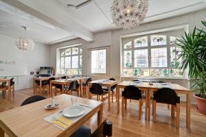 una sala da pranzo con tavoli, sedie e finestre di Pensionsieben Das andere Hotel a Lörrach