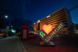 um sinal para um hotel com coração e uma cabine telefónica em Shymkent Grand Hotel em Shymkent