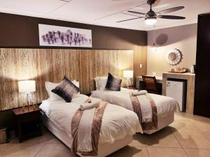 a bedroom with two beds and a ceiling fan at The Wilds Guest House in Hluhluwe