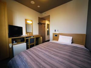 a hotel room with a bed and a television at Hotel Route-Inn Sapporo Kitayojo in Sapporo