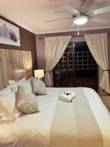 a bedroom with a large white bed with a ceiling fan at The Wilds Guest House in Hluhluwe