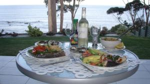 una mesa con dos platos de comida y una botella de vino en Mollymook Beach Waterfront, en Mollymook