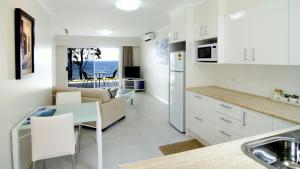 a kitchen and living room with a table and a couch at Mollymook Beach Waterfront in Mollymook