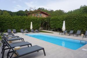 una piscina con sedie a sdraio e ombrelloni di Hotel Rural Sagarlore ad Astigarraga